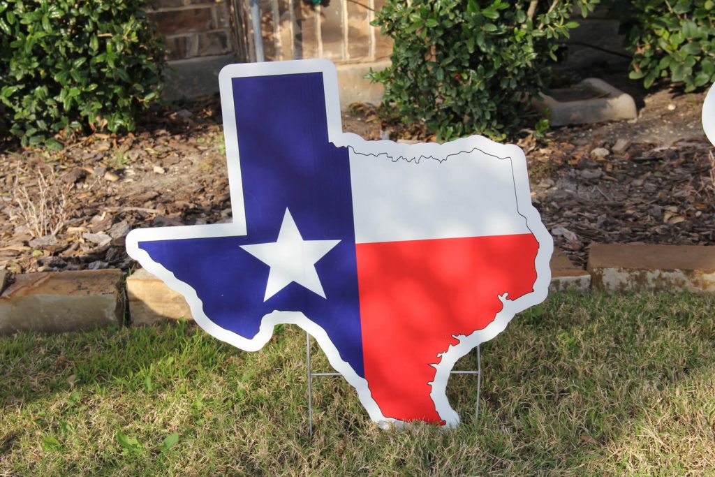 yard sign of Texas state with Texas flag